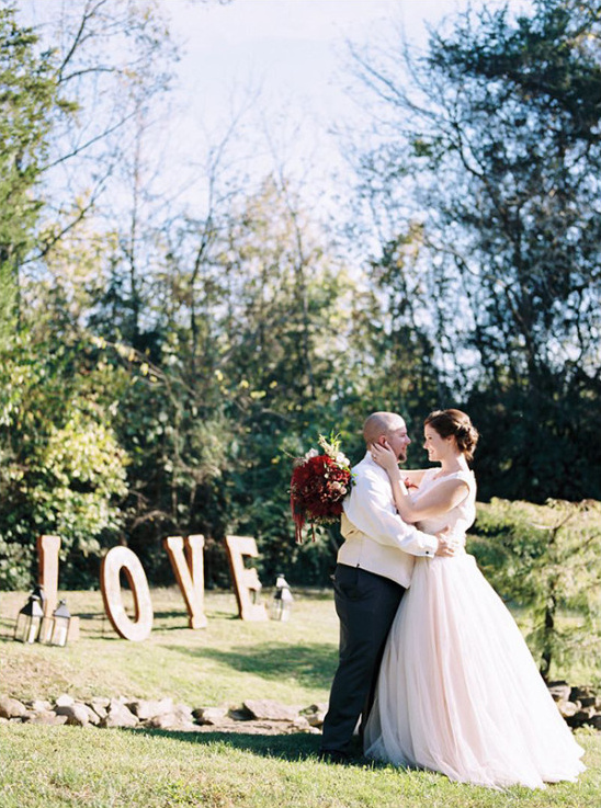 Happy wedding couple hugs by large LOVE letters outside