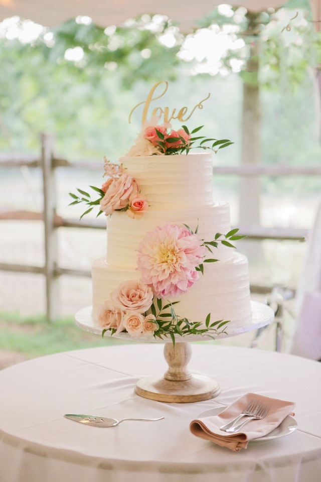 Cute white wedding cake with flowers and love topper