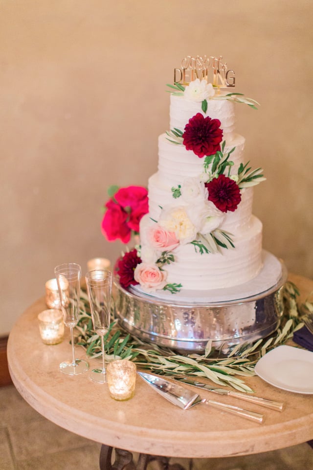 white wedding cake with flowers and gold topper