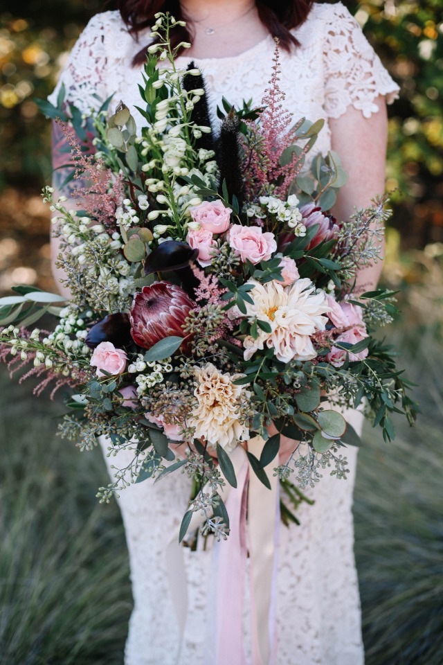Bride holds a lush wedding bouquet with pastel ribbons