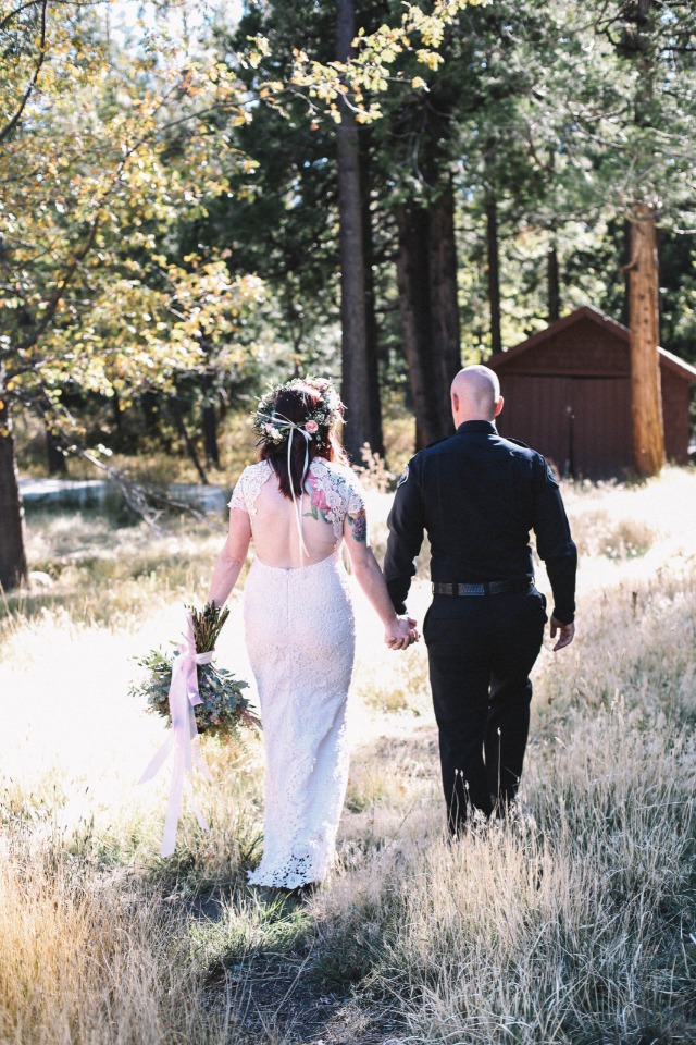 Bride and groom walking hand in hand through a sunlit forest path