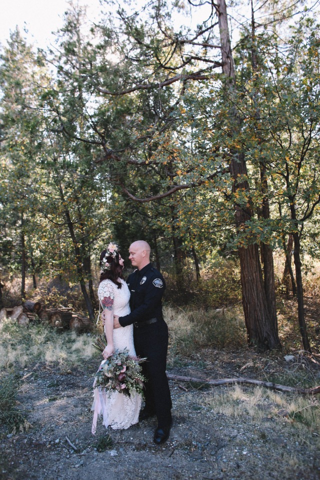Bride and groom embrace in wooded wedding portrait