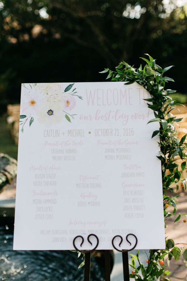wedding program sign with floral garland