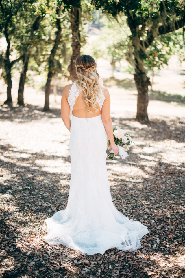 Bride in white wedding dress standing in a sunny forest