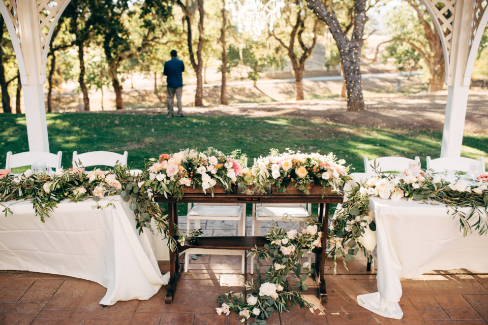 Wedding table with floral arrangements outdoors, sunlight