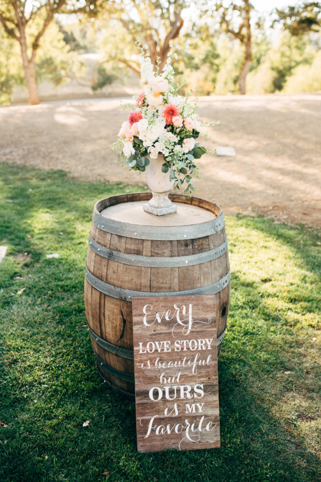 Wedding decor with floral arrangement and a love quote on a barrel