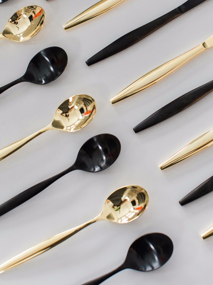 Elegant black and gold spoons artfully arranged on a white background