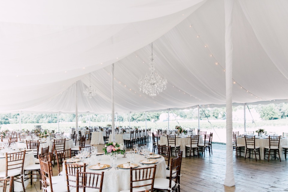 Gorgeous tent reception with chandeliers and bistro lights