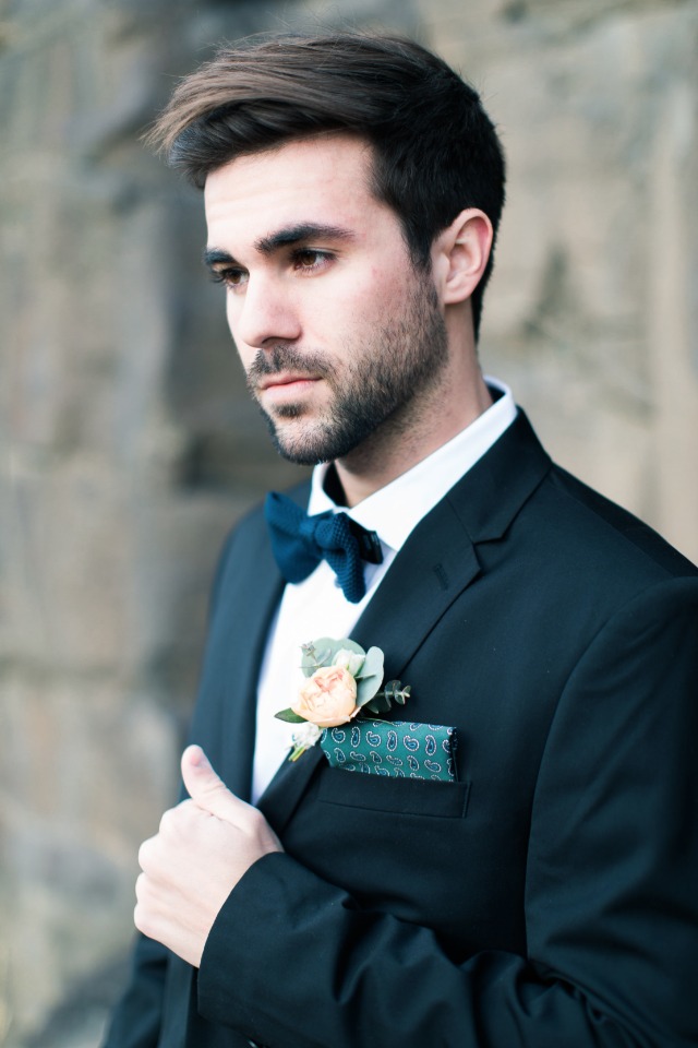 Dapper groom in dark suit with blue bow tie