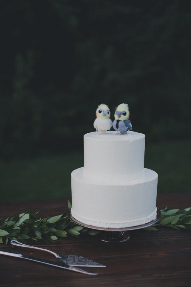 simple white wedding cake and cute bird cake topper