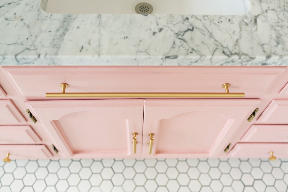 pink and gold bathroom cabinets topped with a little marble