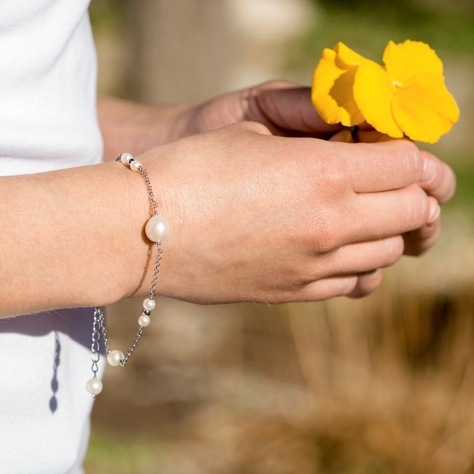 Elegant pearl bracelet on wrist holding flower