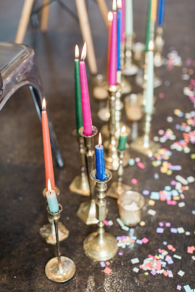 Aisle decor with colorful candles, brass candle sticks and confetti