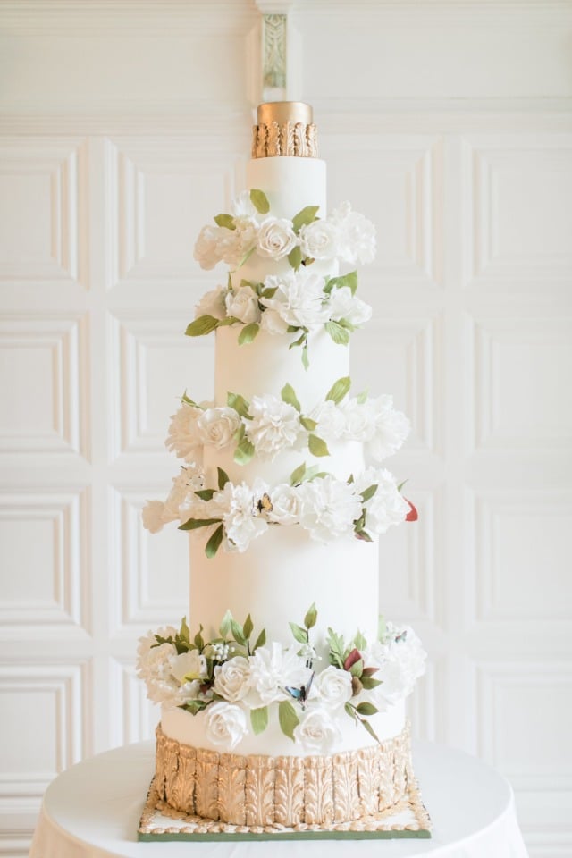 gold and white wedding cake with flower and butterfly accents