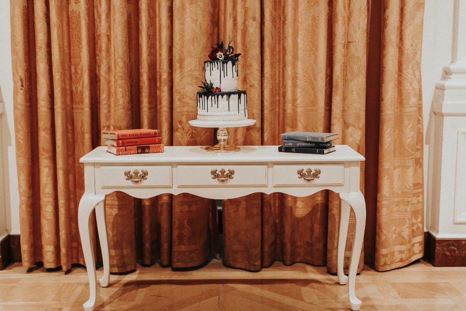 Elegant dessert table with dripped cake and vintage books