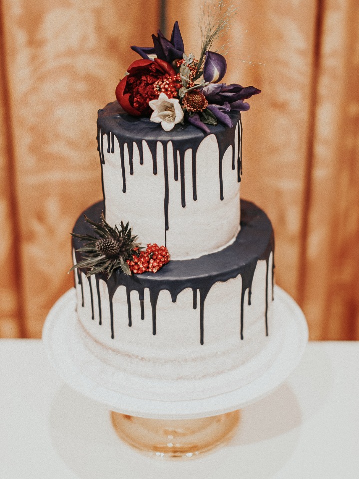 Two tier wedding cake with dark chocolate drip and flowers