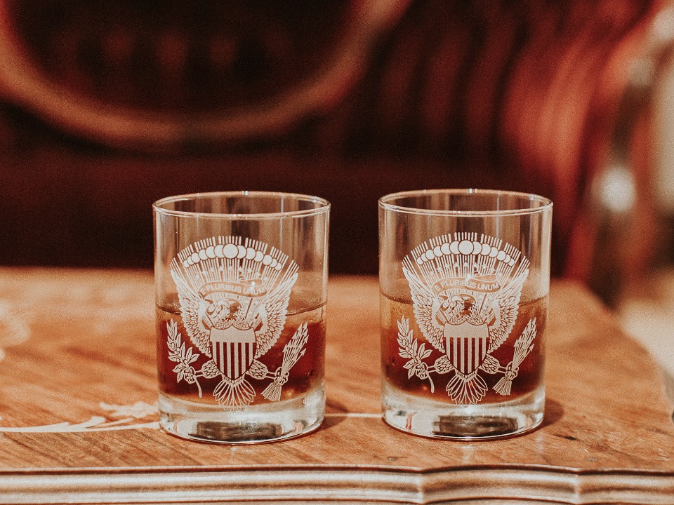 Two glasses with Presidential Seal whiskey on wood