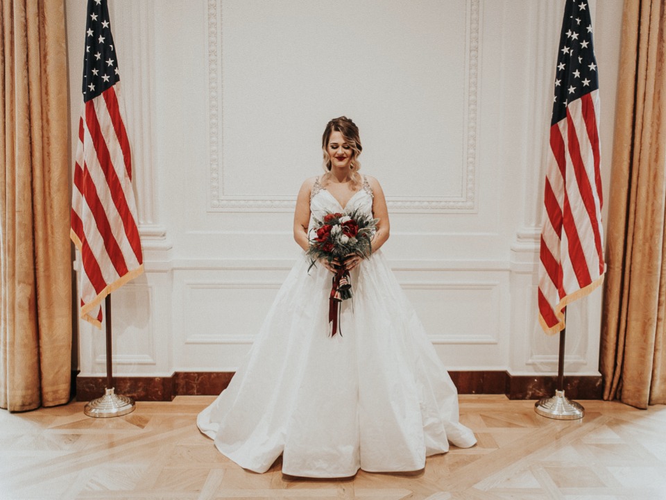 Bride in white dress with American flags background