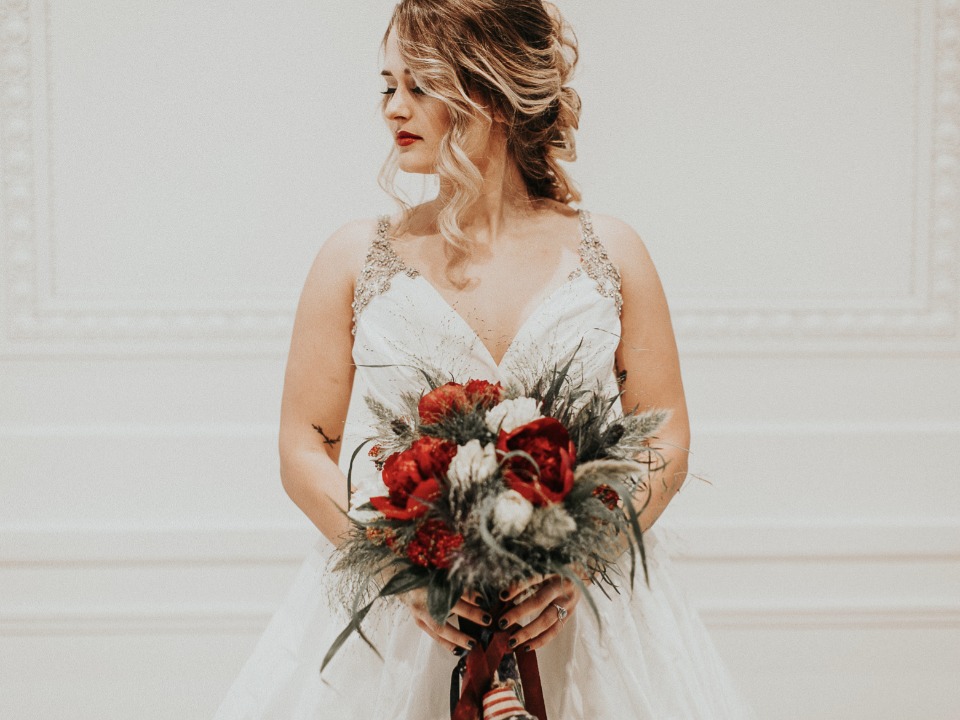 Elegant bride holding red and white flower bouquet