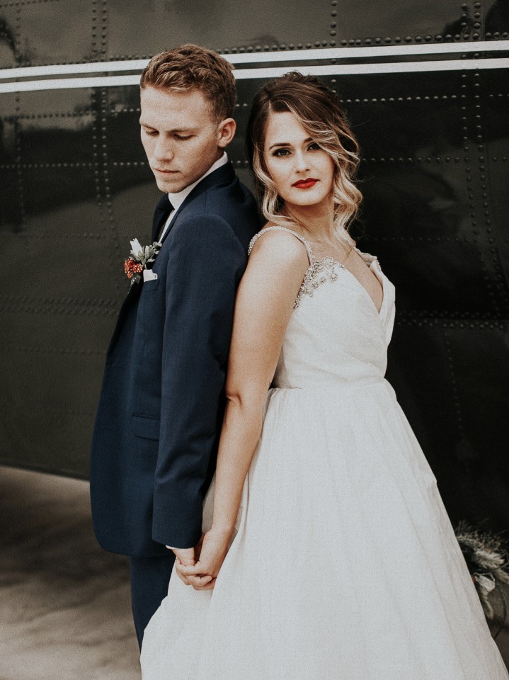 Bride and groom hold hands back to back at wedding