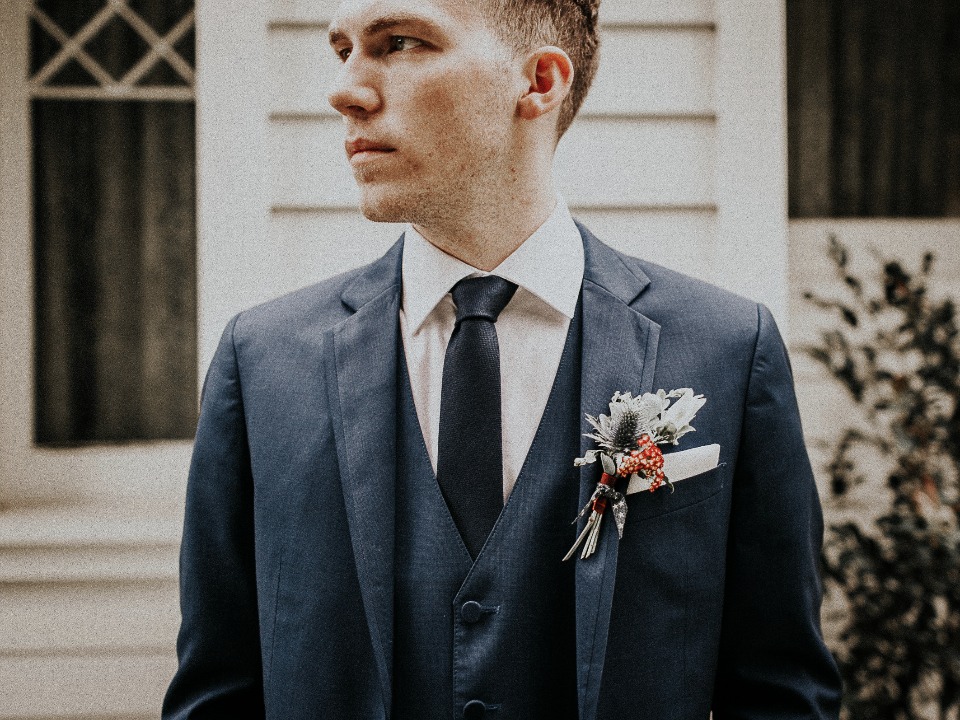 Groom in tailored blue suit with a boutonniere detail