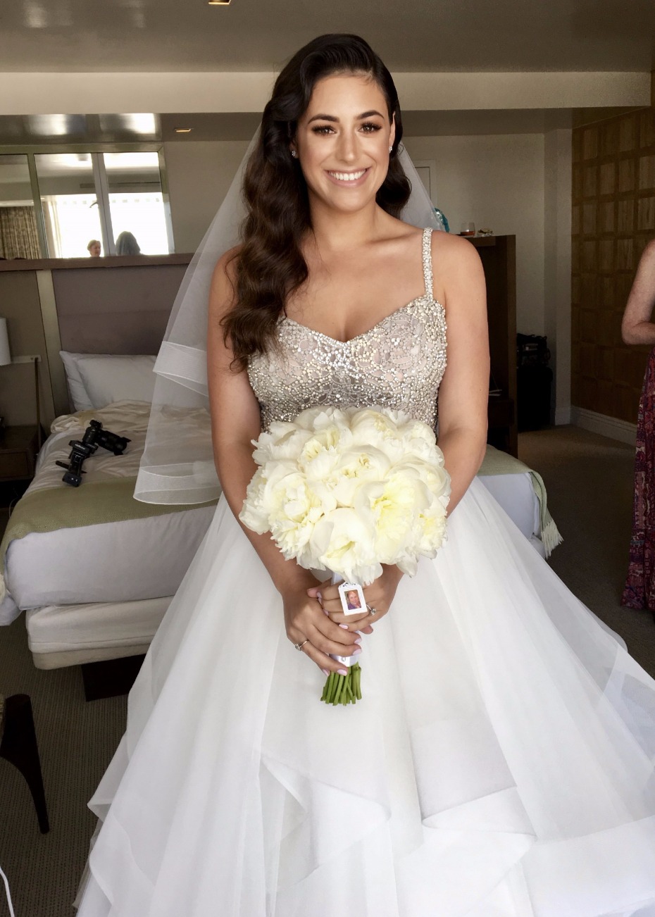 Bride in wedding dress holding peony bouquet smiling