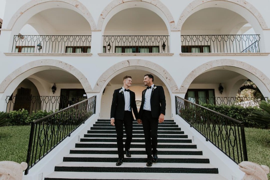 Newlyweds walk hand in hand down staircase at wedding venue