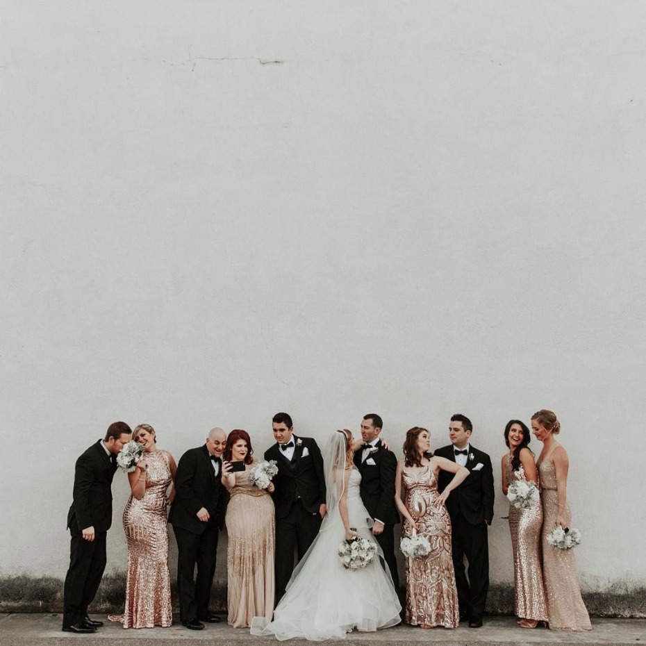 Wedding party poses against a stark white wall backdrop