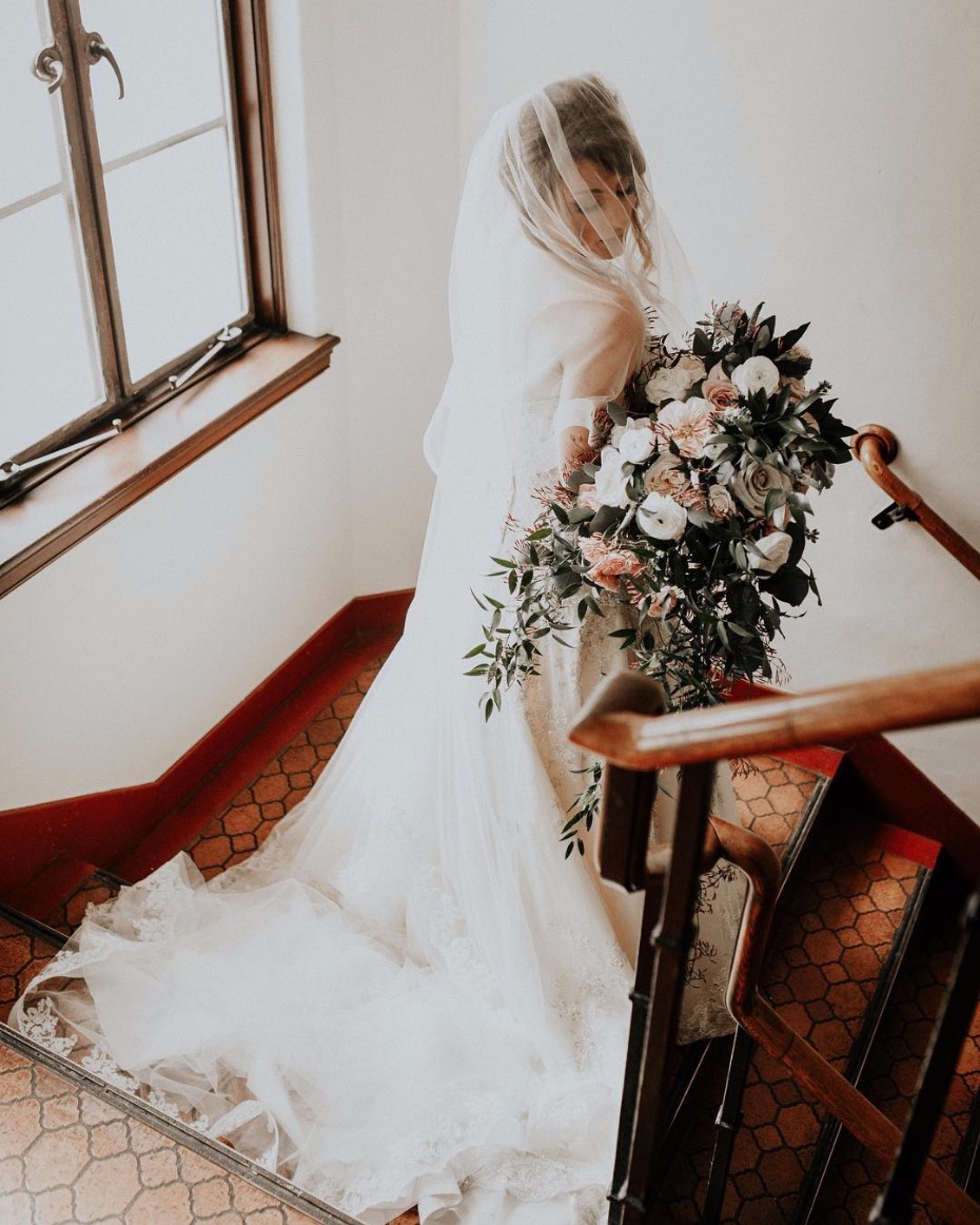 Bride with veil and cascading bouquet on staircase