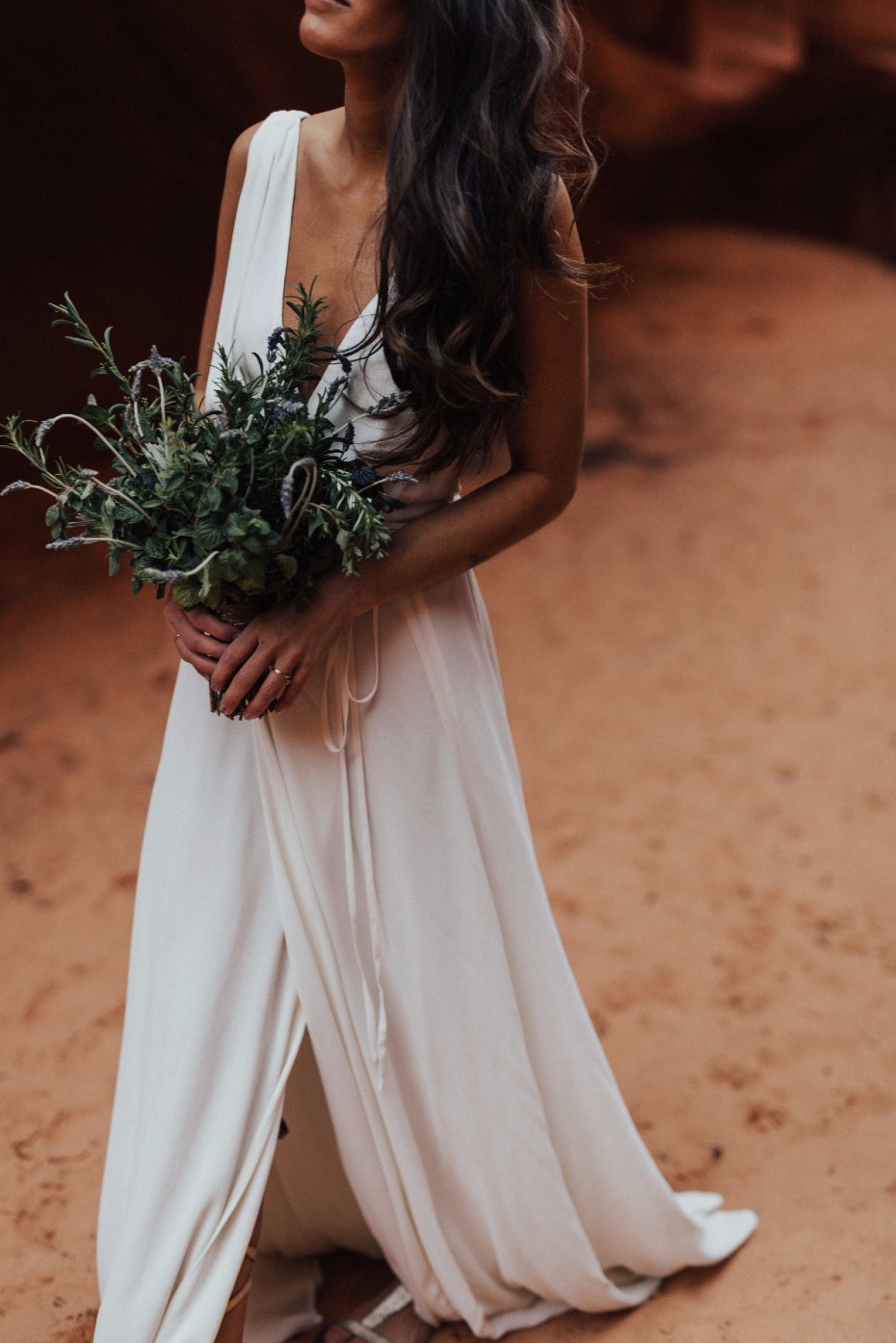 Woman in flowing dress holding green bouquet outdoors