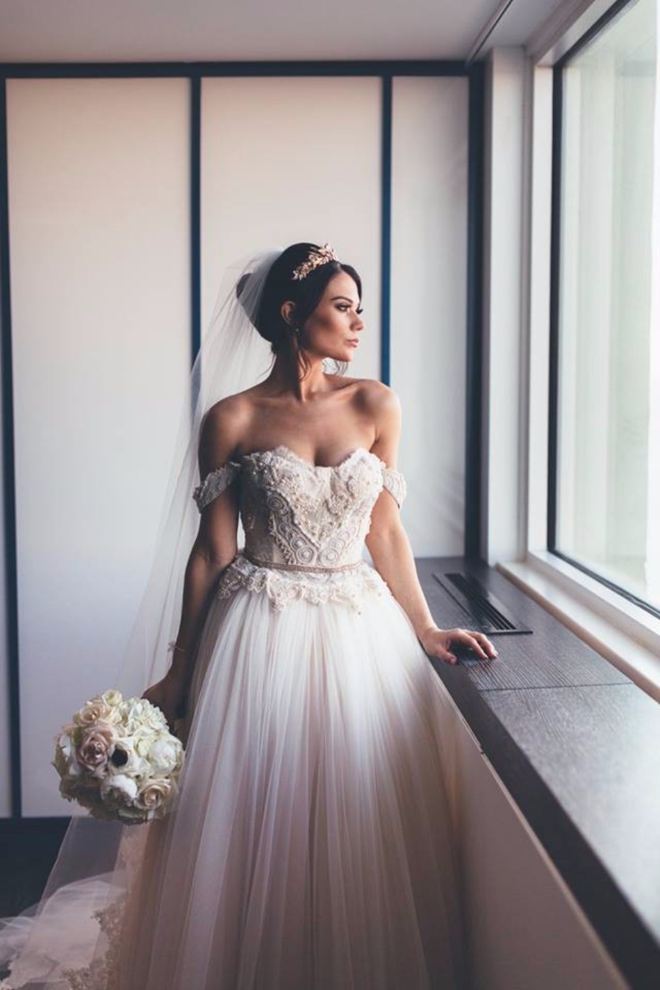 Elegant bride in off shoulder wedding dress looking out