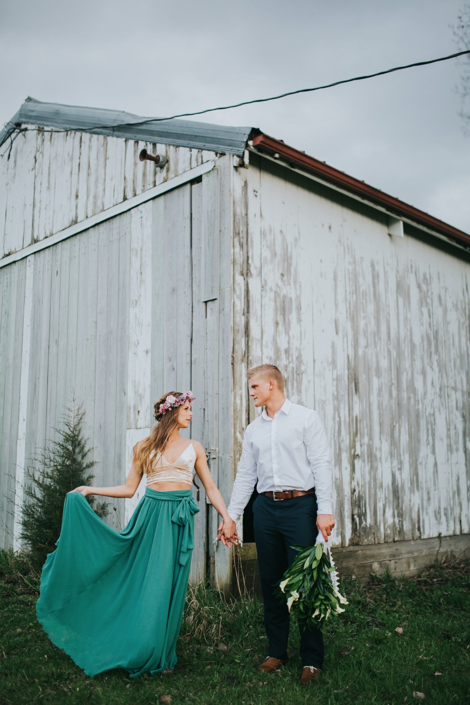 Couple holding hands near rustic barn wedding photo