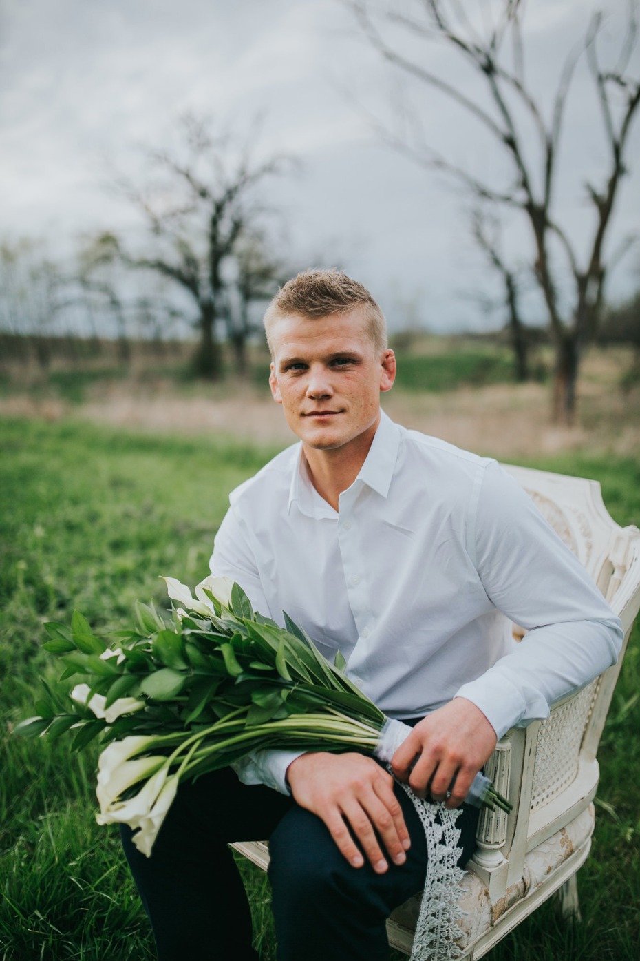 Man with lilies sits outdoors on a chair in nature