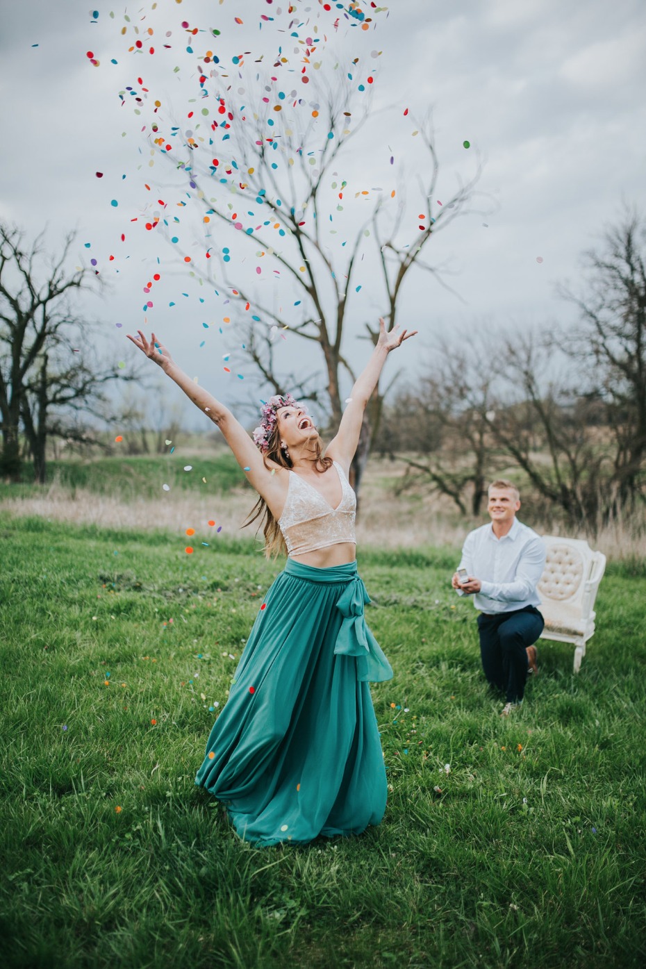 Joyful bride throws confetti after proposal in green field