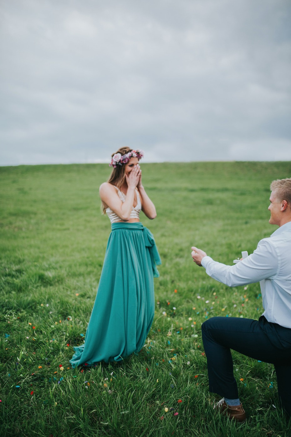 Woman surprised by romantic proposal on green field