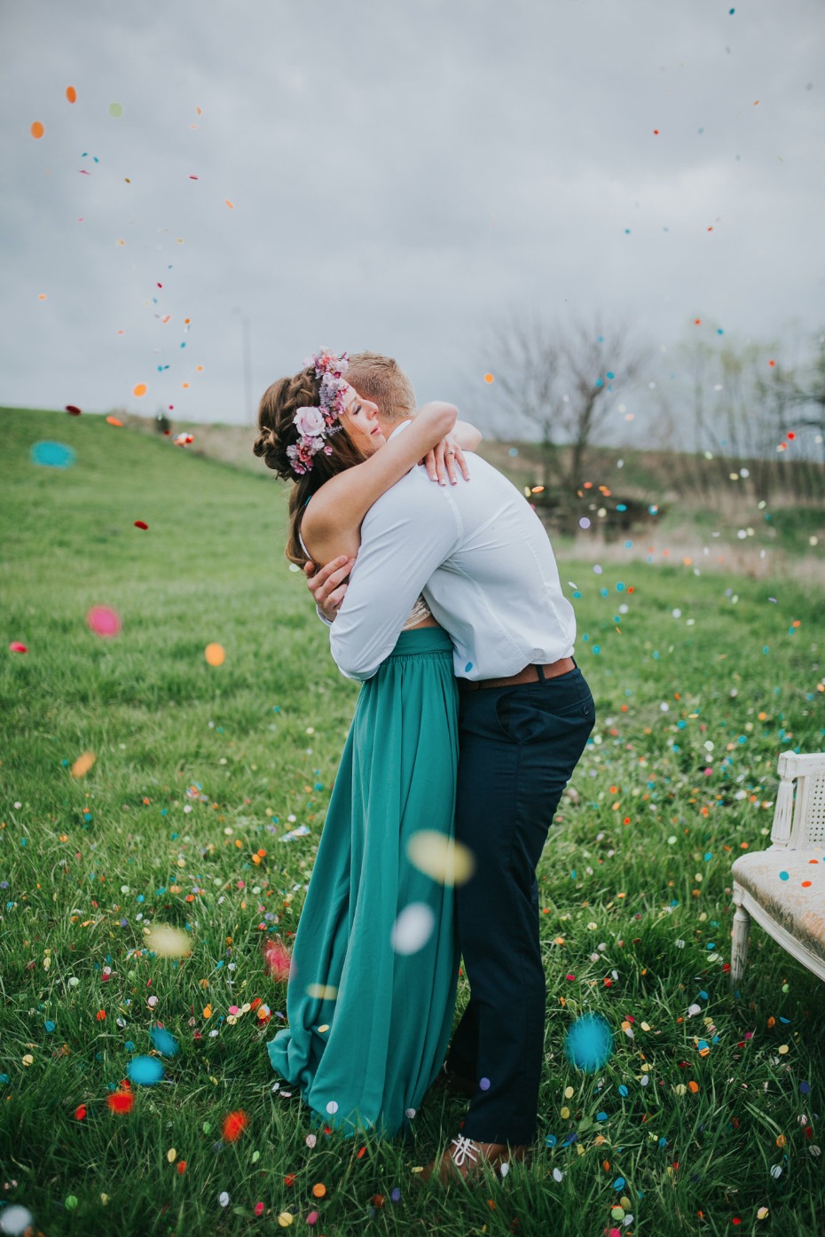 Bride and groom embracing in confetti meadow field