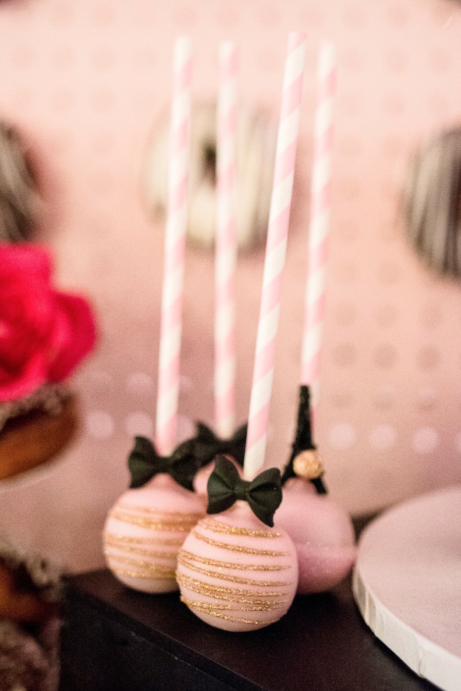 Pink cake pops with gold glitter and bows on sticks