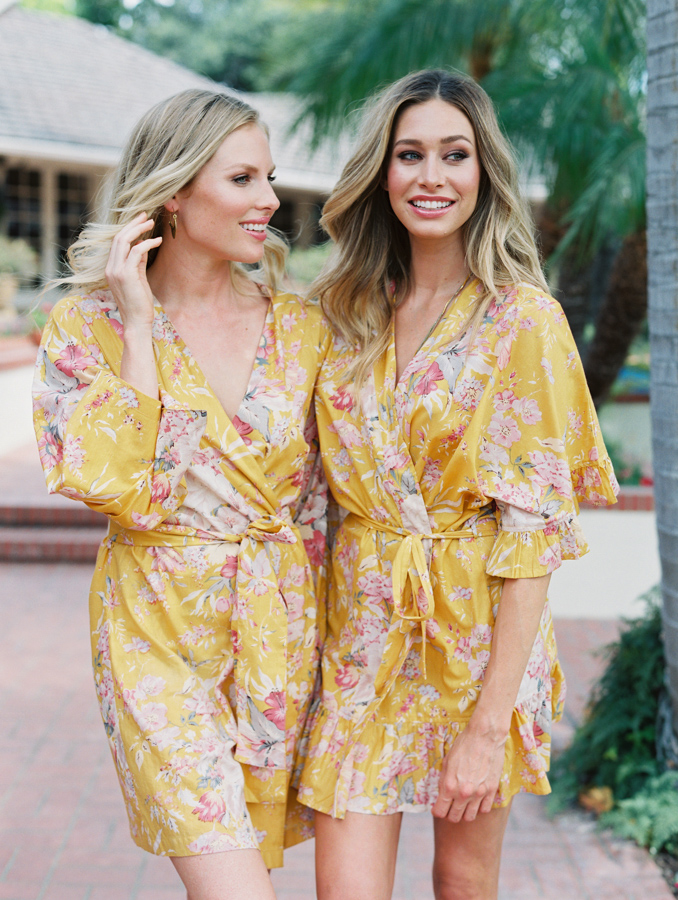 Two women in yellow floral print robes smiling