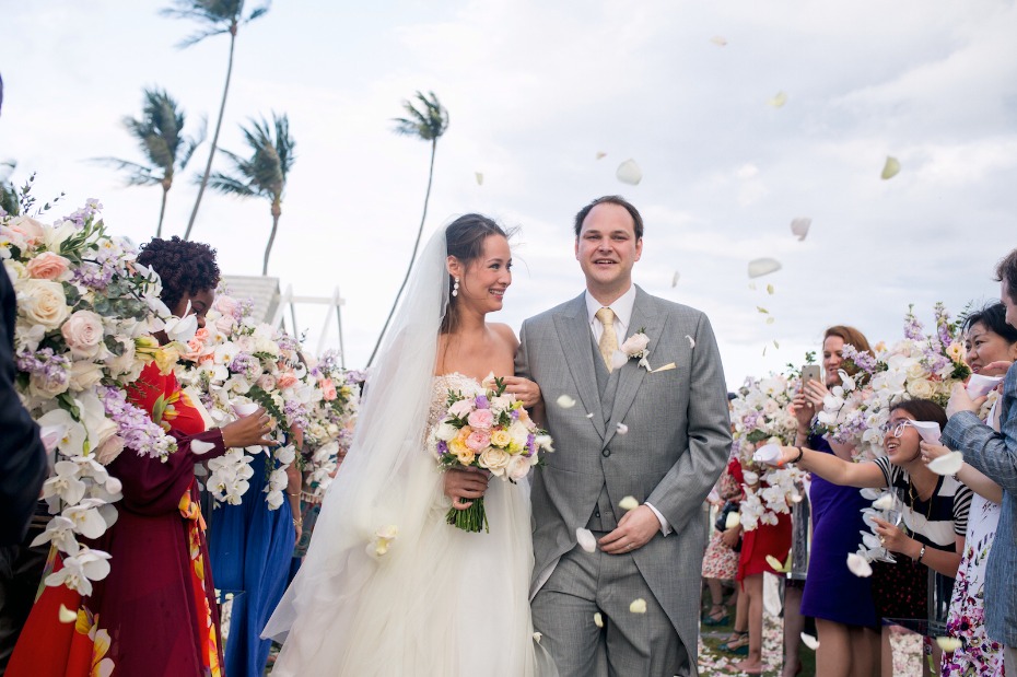 Bride and groom walk down aisle with flower petals