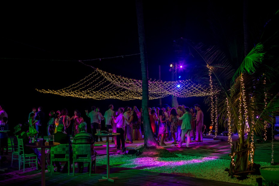 People dancing at a night party with lights and palms