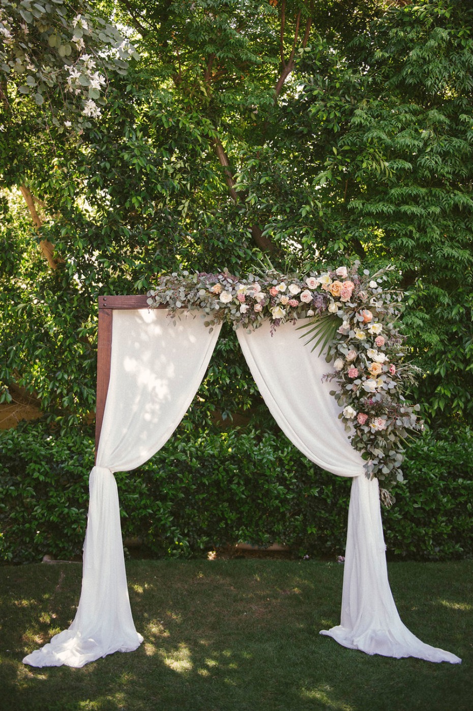 Picture perfect arch with draped fabric and garden florals