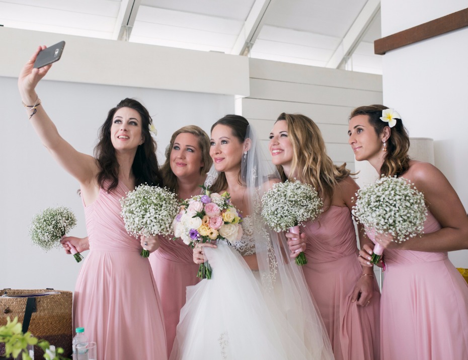 Bride and bridesmaids taking selfie on wedding day