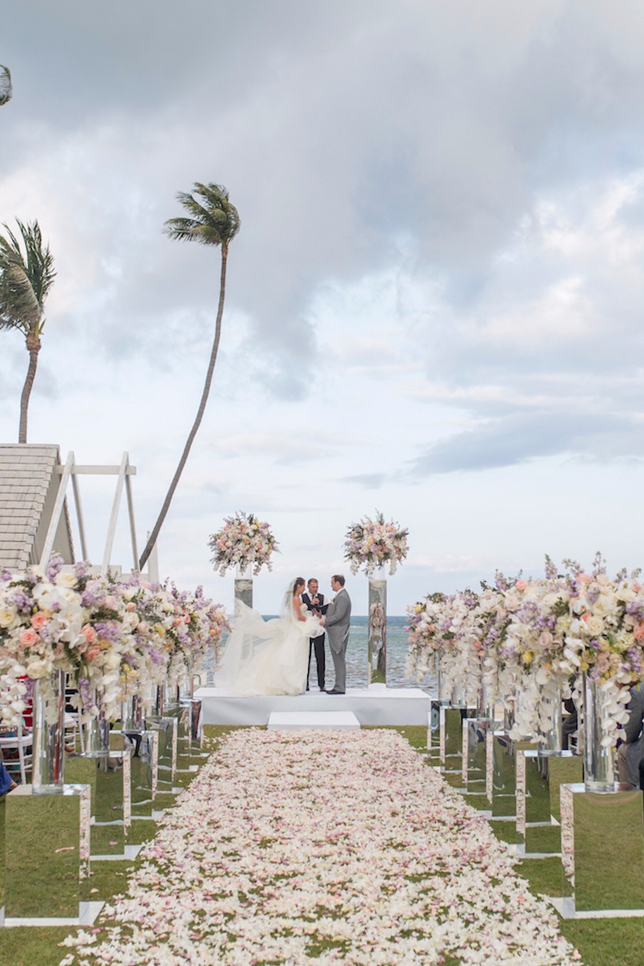Outdoor oceanfront wedding ceremony with flower petals
