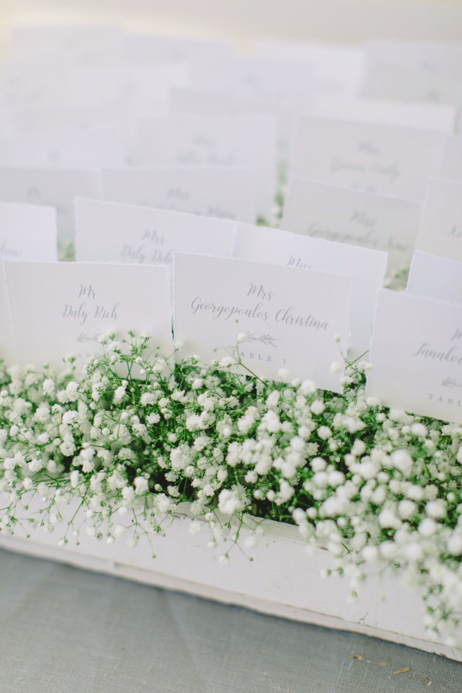 Wedding place cards in a white box with small white flowers