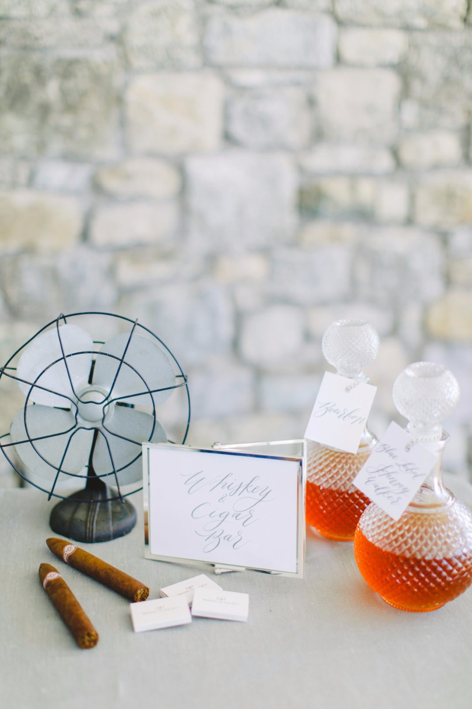 Whiskey and cigar bar setup with cigars, a fan, and bottles