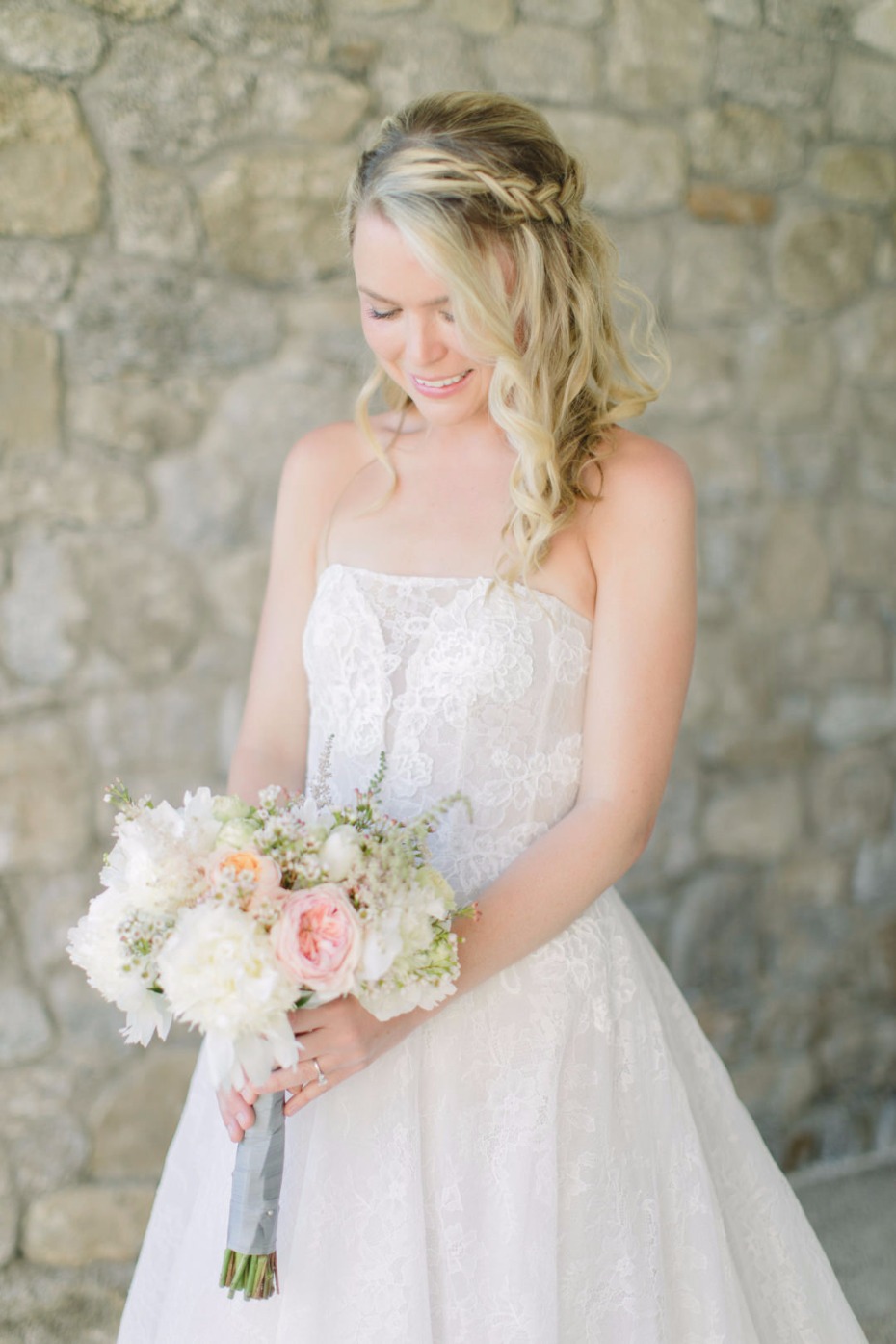 Bride in a strapless gown with a floral bouquet smiling on wedding day