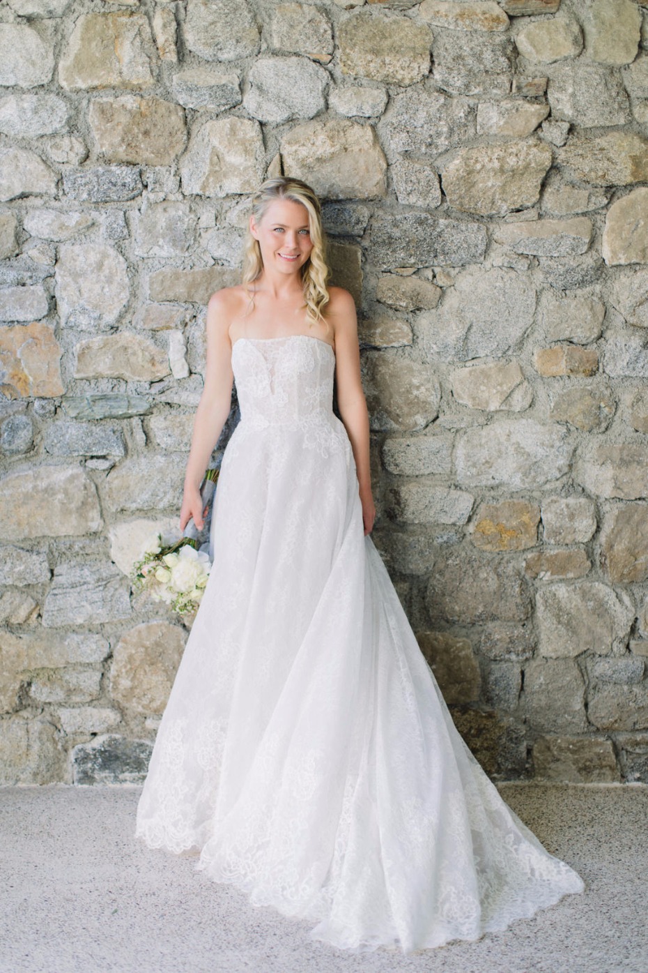 Blonde bride in elegant strapless wedding dress smiles beautifully