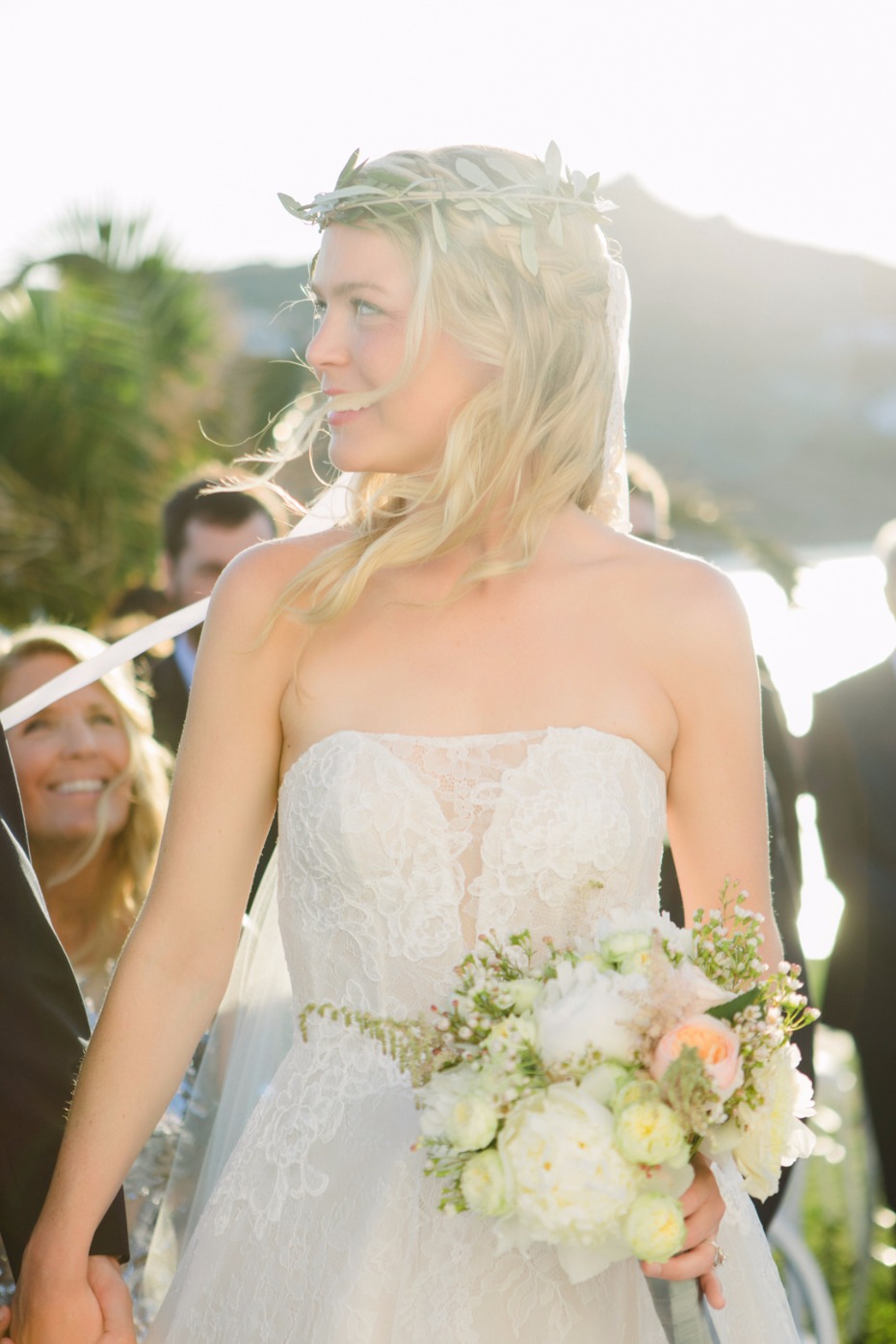 Smiling bride in a lace wedding dress with floral bouquet