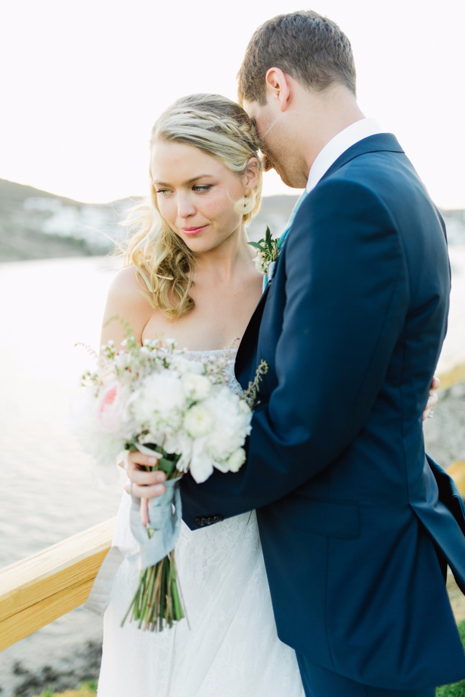 Bride and groom embrace on their wedding day near the water