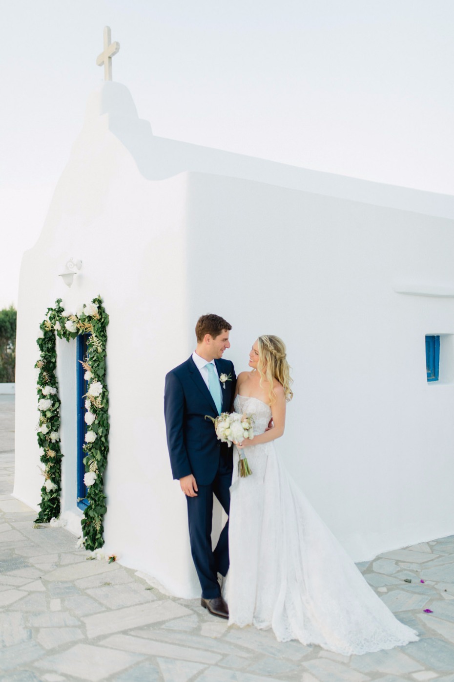 Elegant bride and groom pose in front of a white church